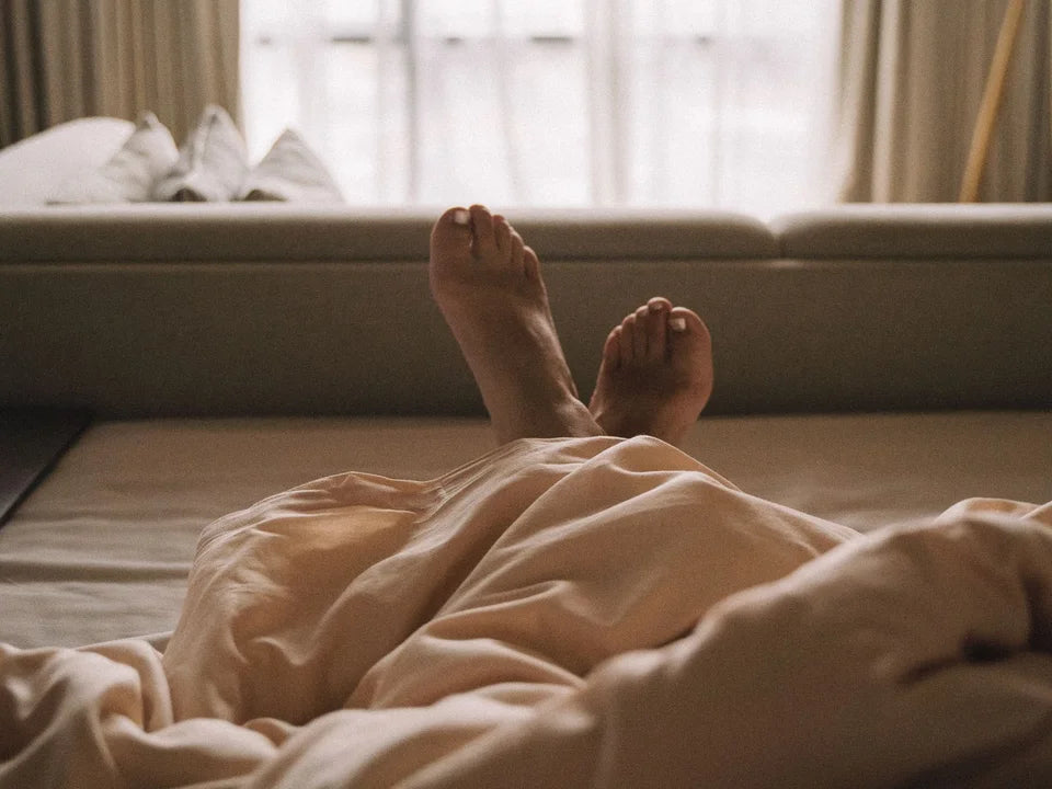 Feet resting under a blanket by a window